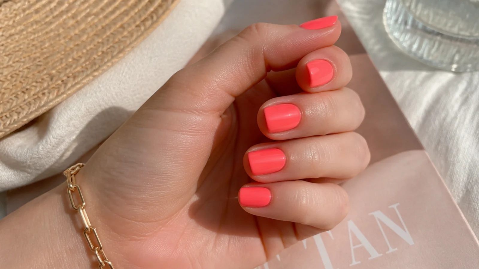 Short squoval nails in neon coral pink orange with a smooth opaque finish