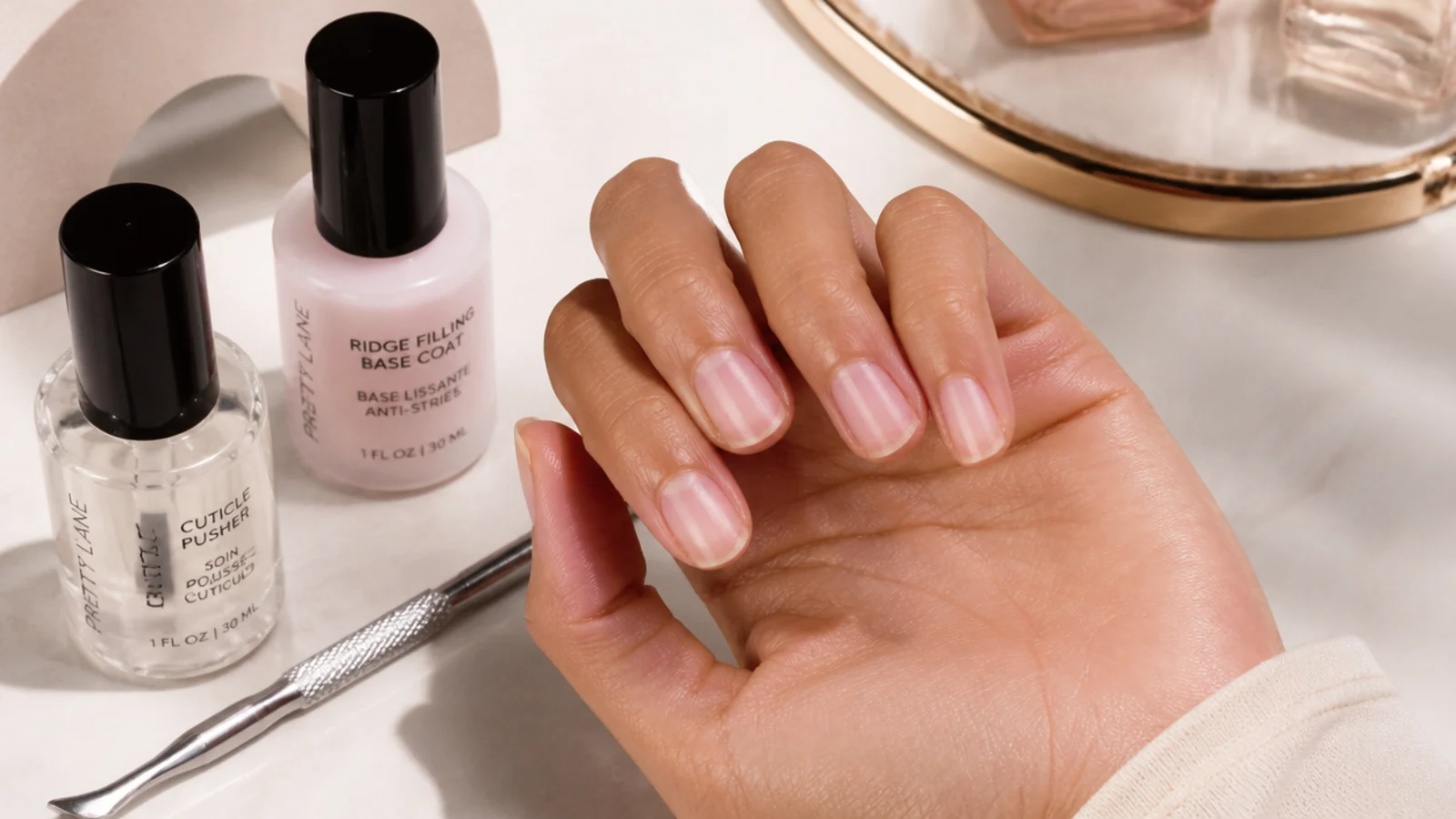 Cuticle pusher and ridge filling base coat beside short nails prepped for dark fall polish