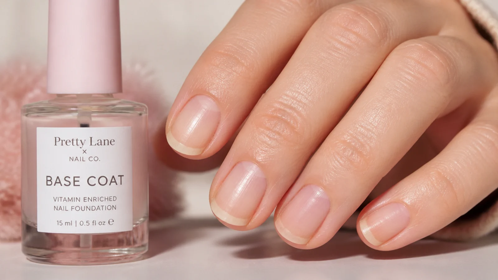 Short nail showing tip wear and a stained free edge next to a bottle of base coat