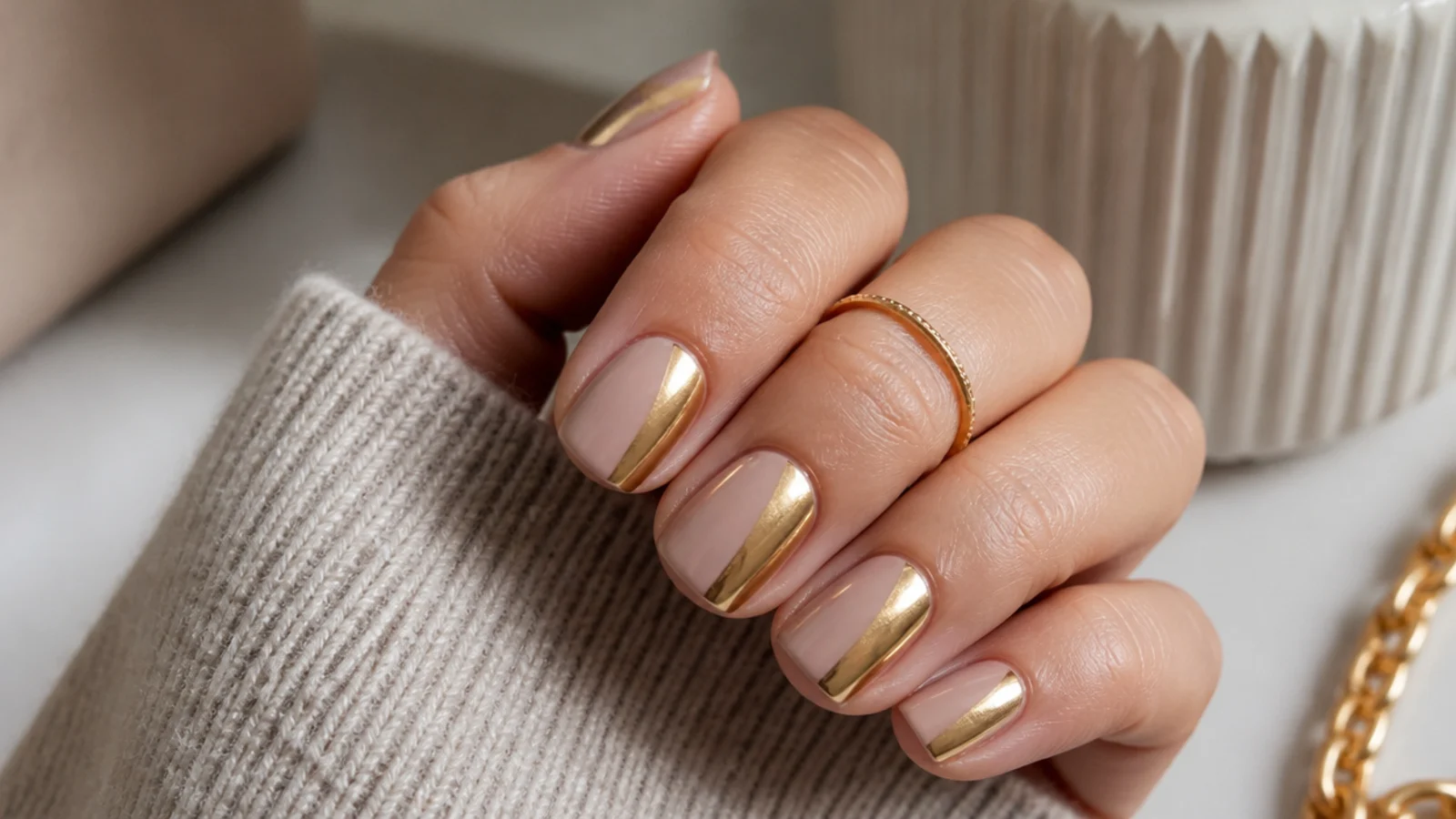 Short squoval nails in warm nude with gold chrome painted on the outer third of each nail