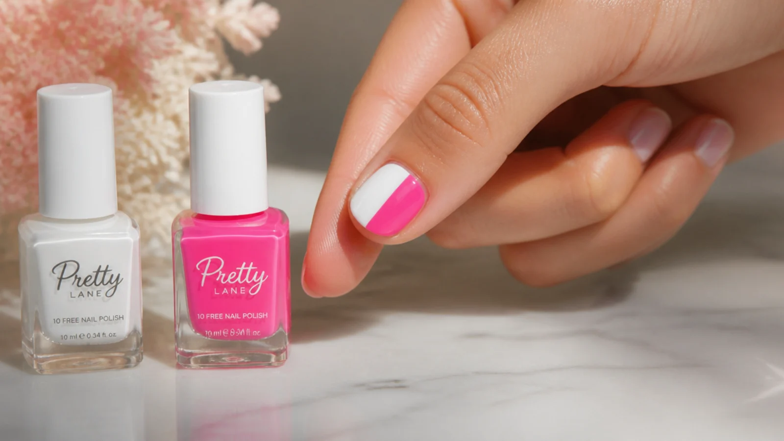 Bottle of white base polish beside a neon pink bottle with a short nail half painted in each