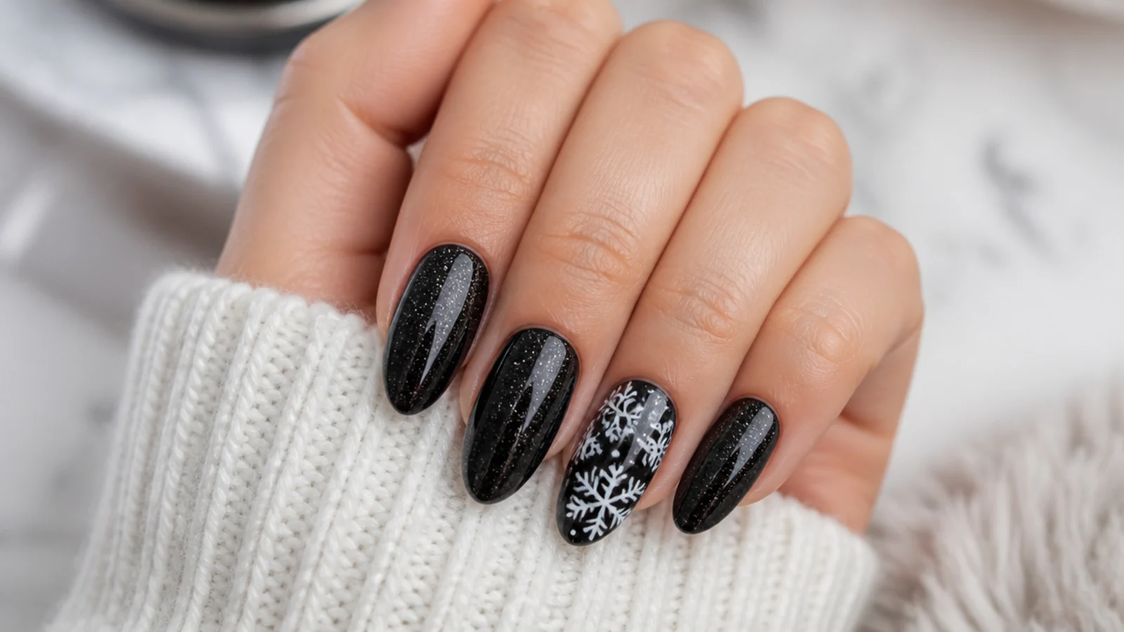Black nails with silver glitter and white snowflakes on an accent finger