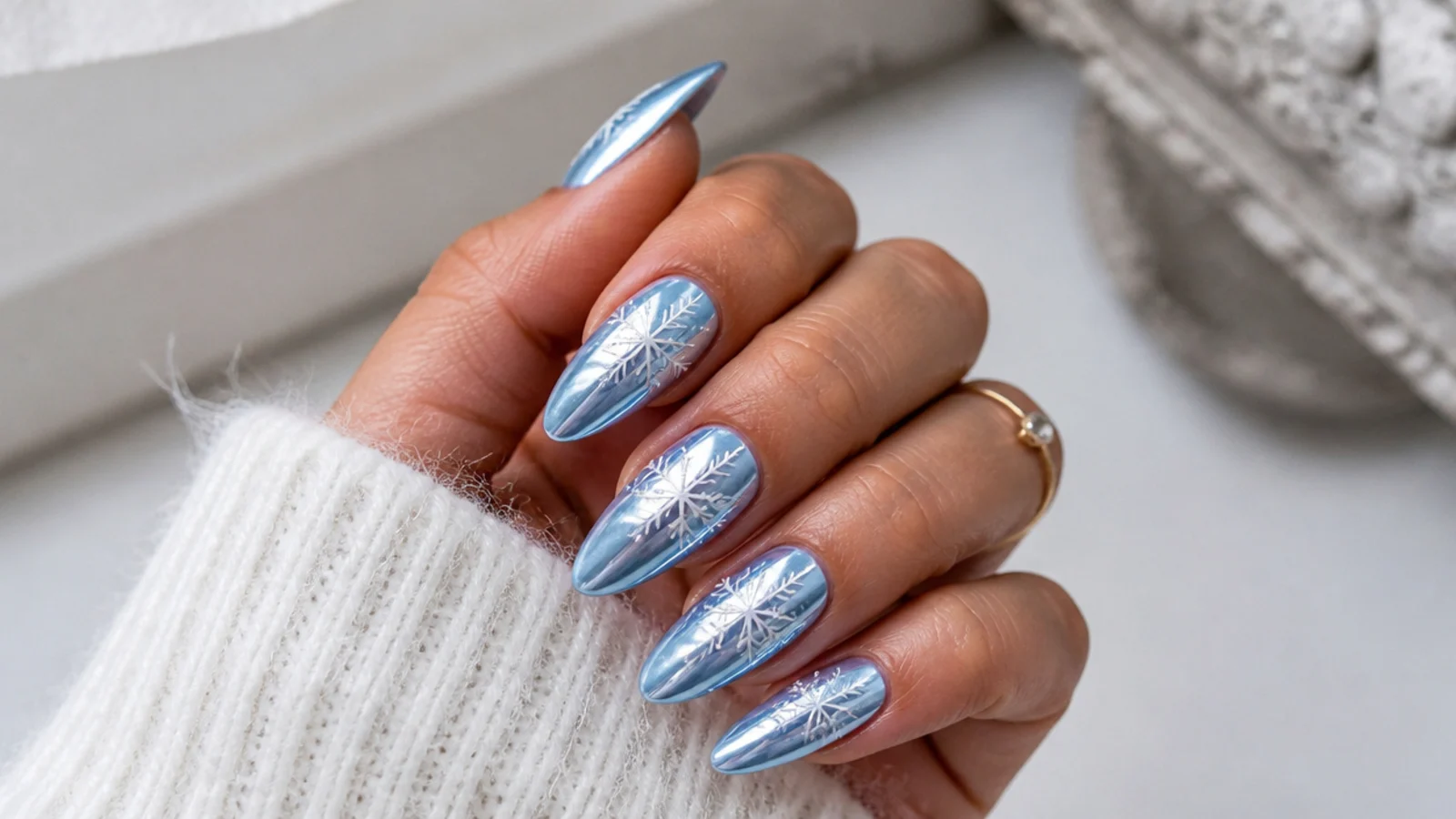 Icy blue chrome snowflake nails with a mirror finish and white flakes