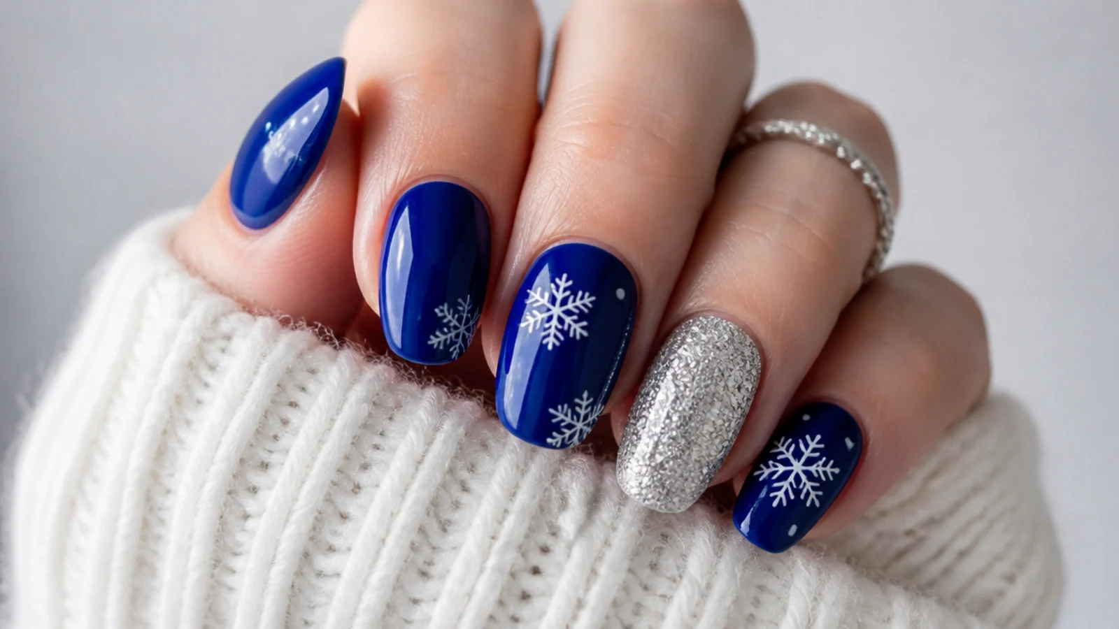 Bright cobalt blue snowflake nails with silver glitter accent nail