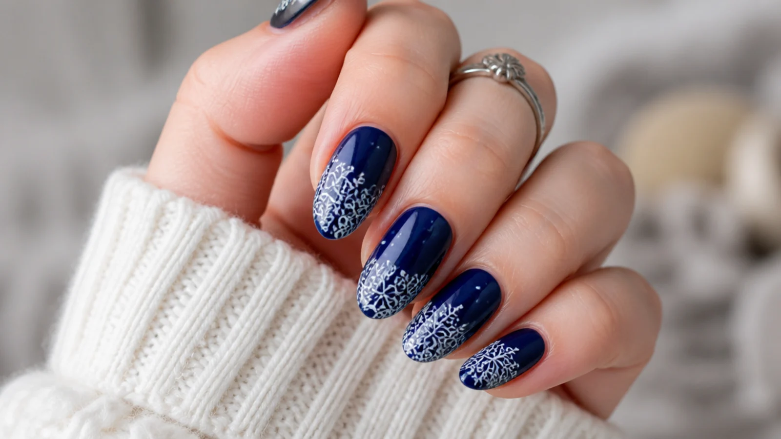 Royal blue nails with intricate white lace-like snowflake detailing
