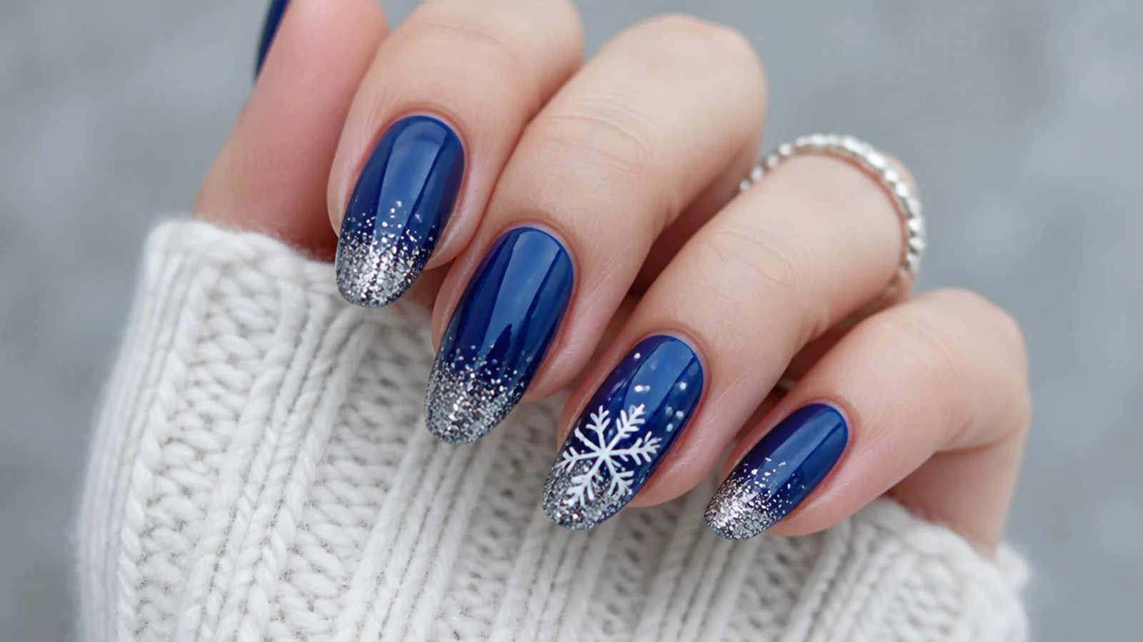Navy nails with silver glitter tips and a small white snowflake