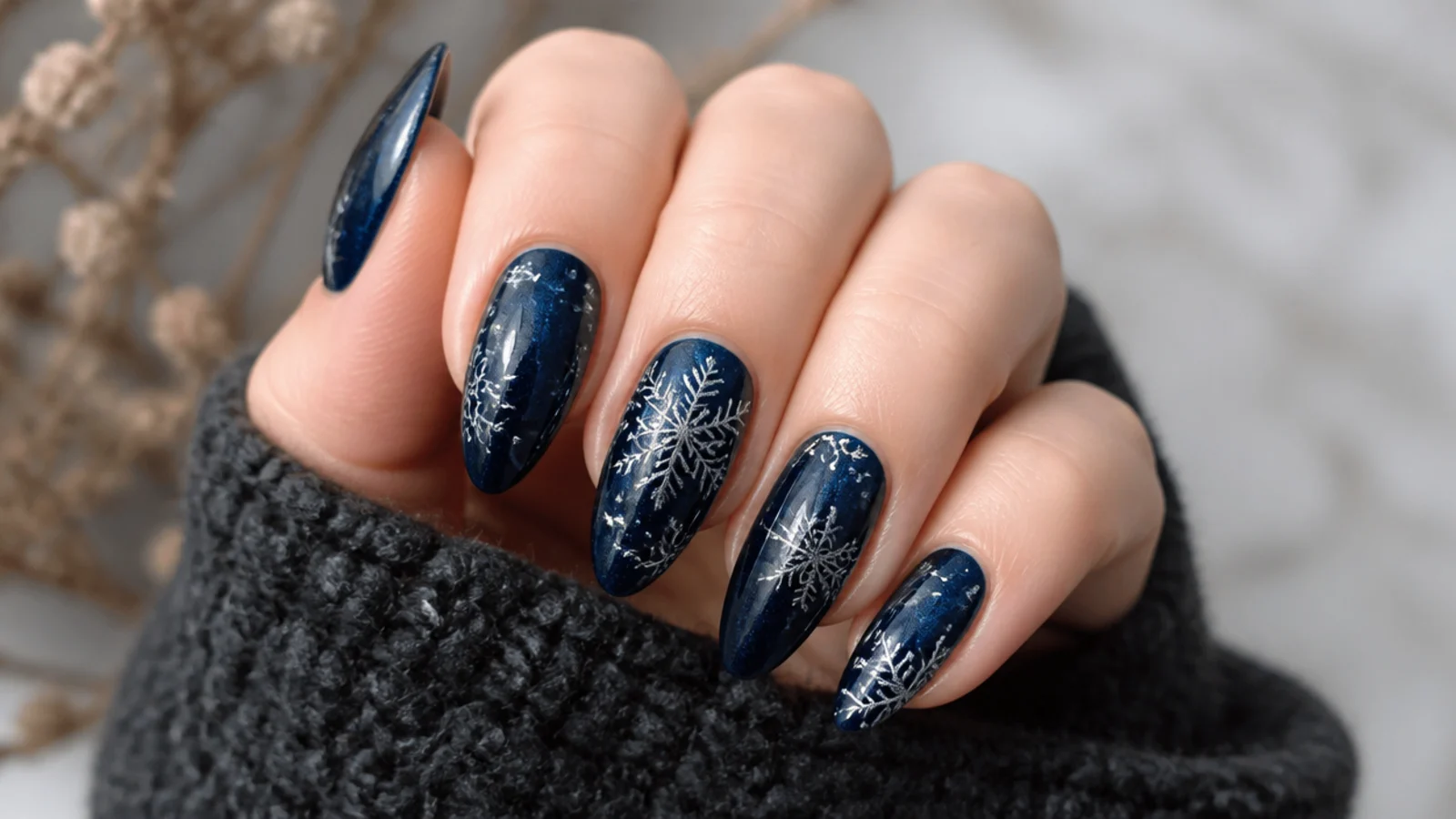 Deep blue-black nails with silver and white snowflakes and a moody finish
