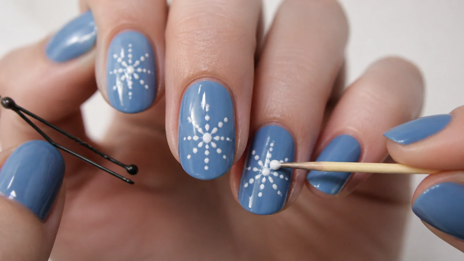 A bobby pin and toothpick making snowflake dots on a blue nail