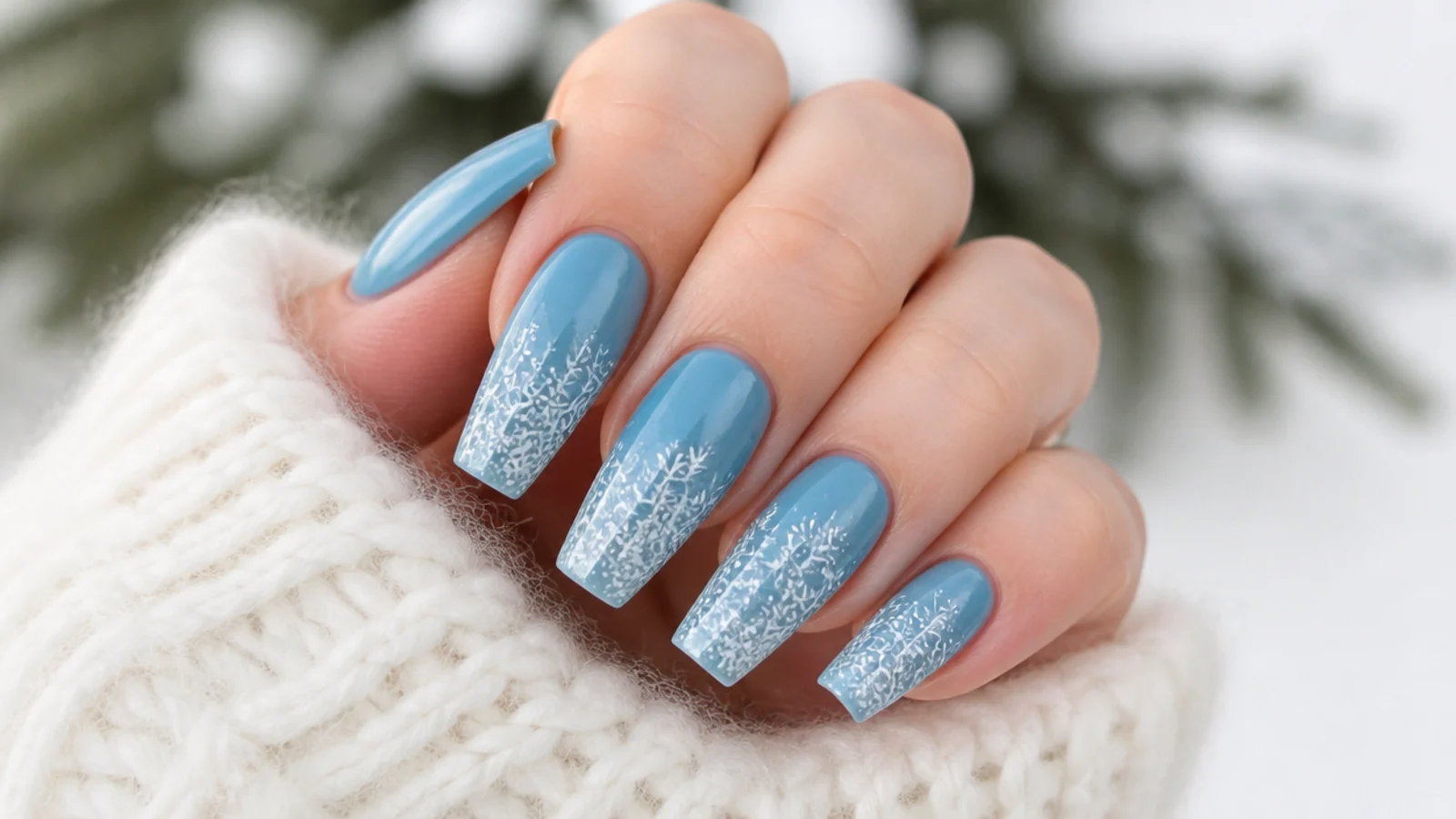 White snowflakes clustered at the tips over an icy blue base on coffin nails