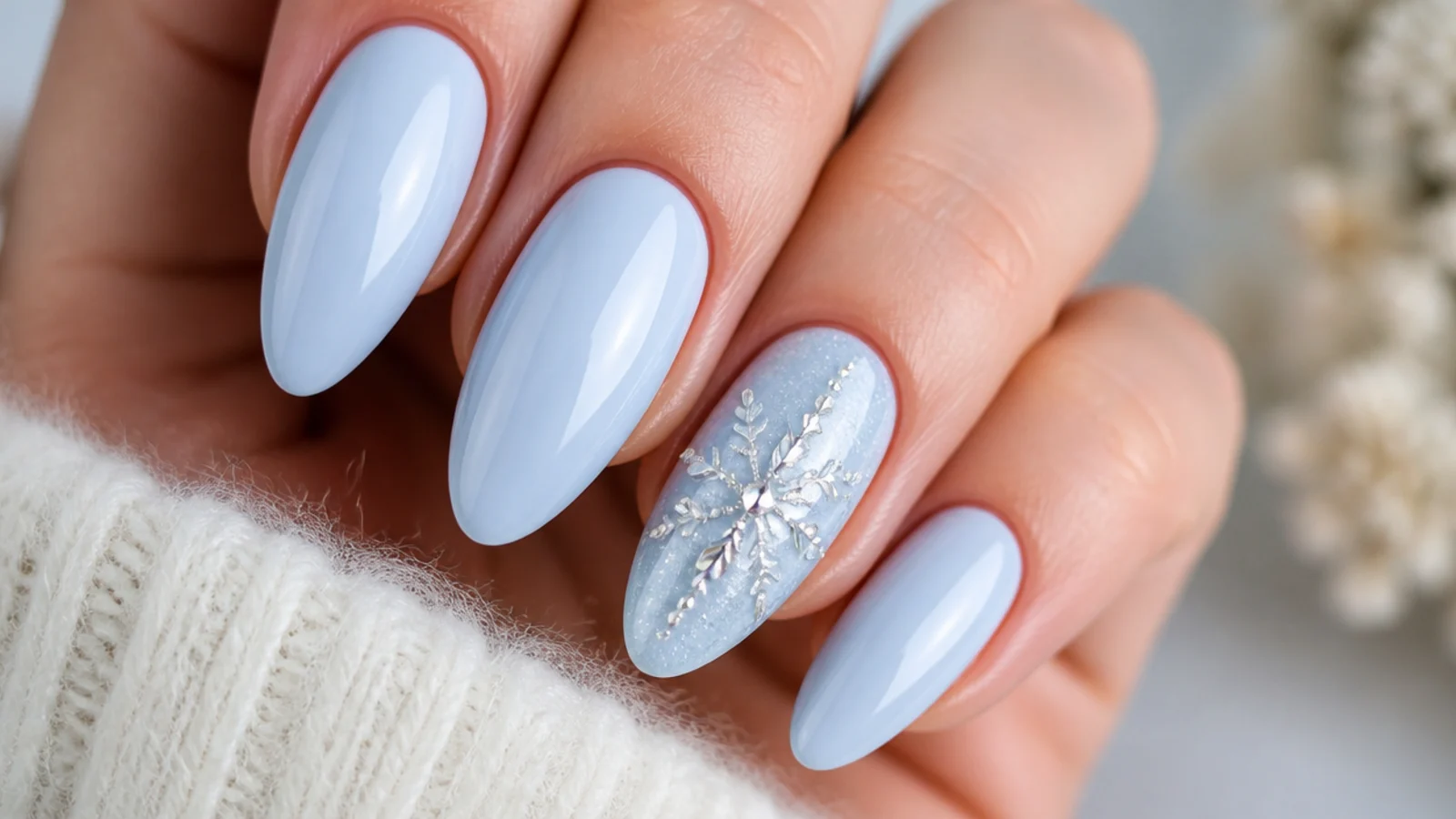 A rhinestone-built snowflake on an icy blue accent nail among solid nails