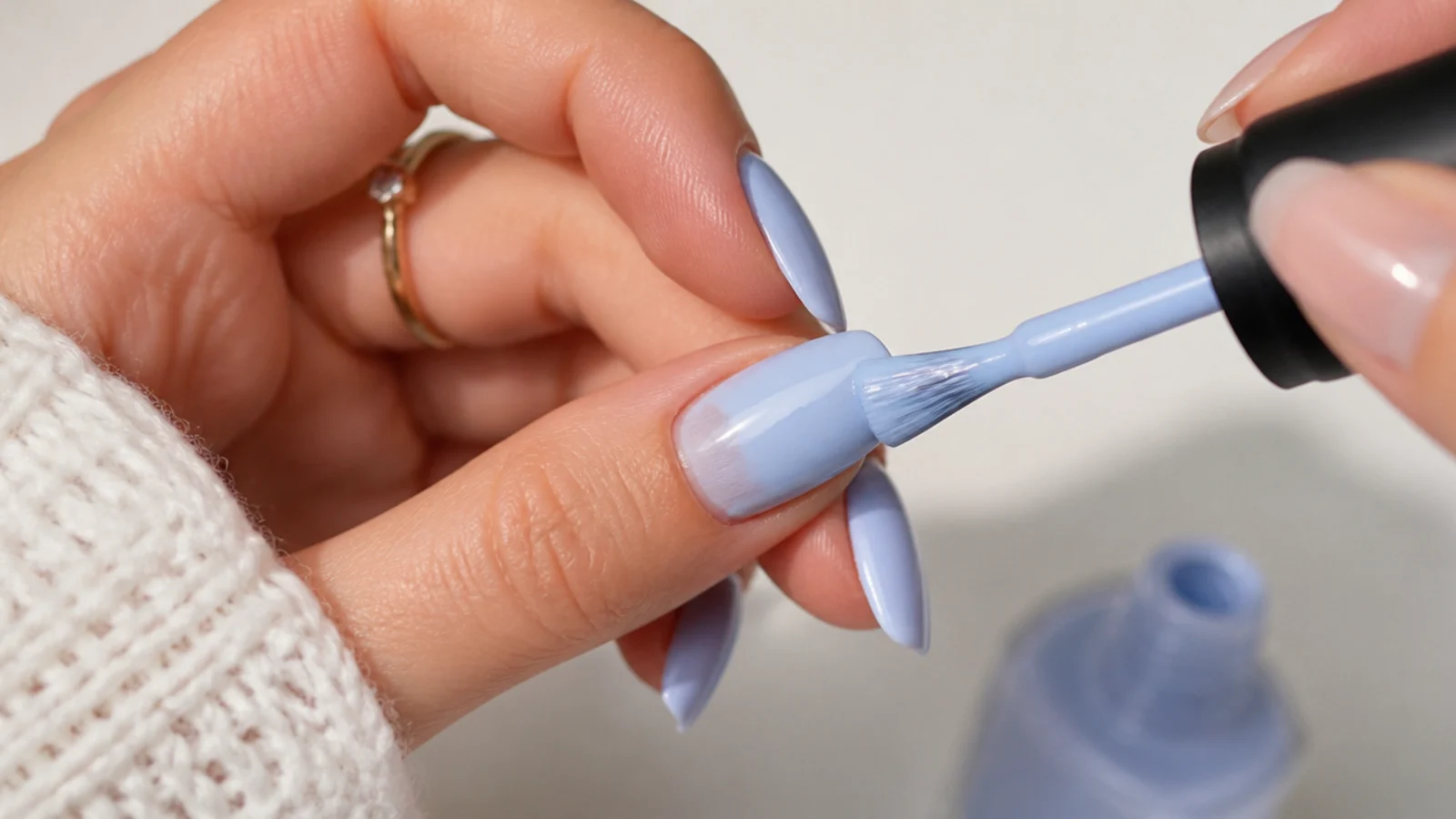 An icy blue gel base color being painted over the whole nail