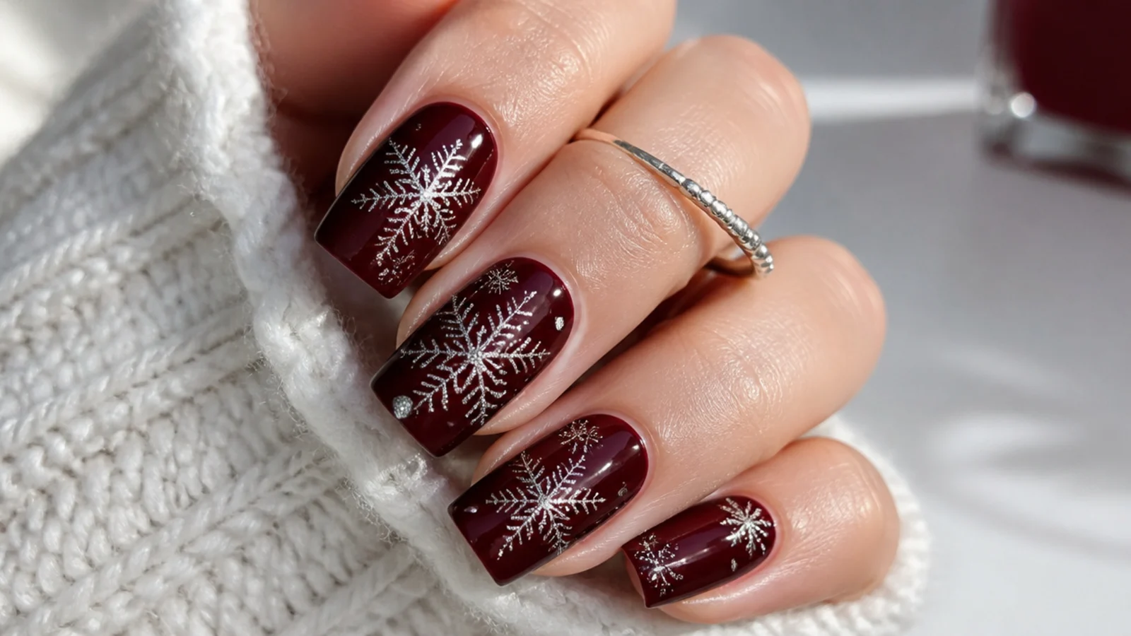 Deep burgundy nails with fine silver snowflakes on a square shape