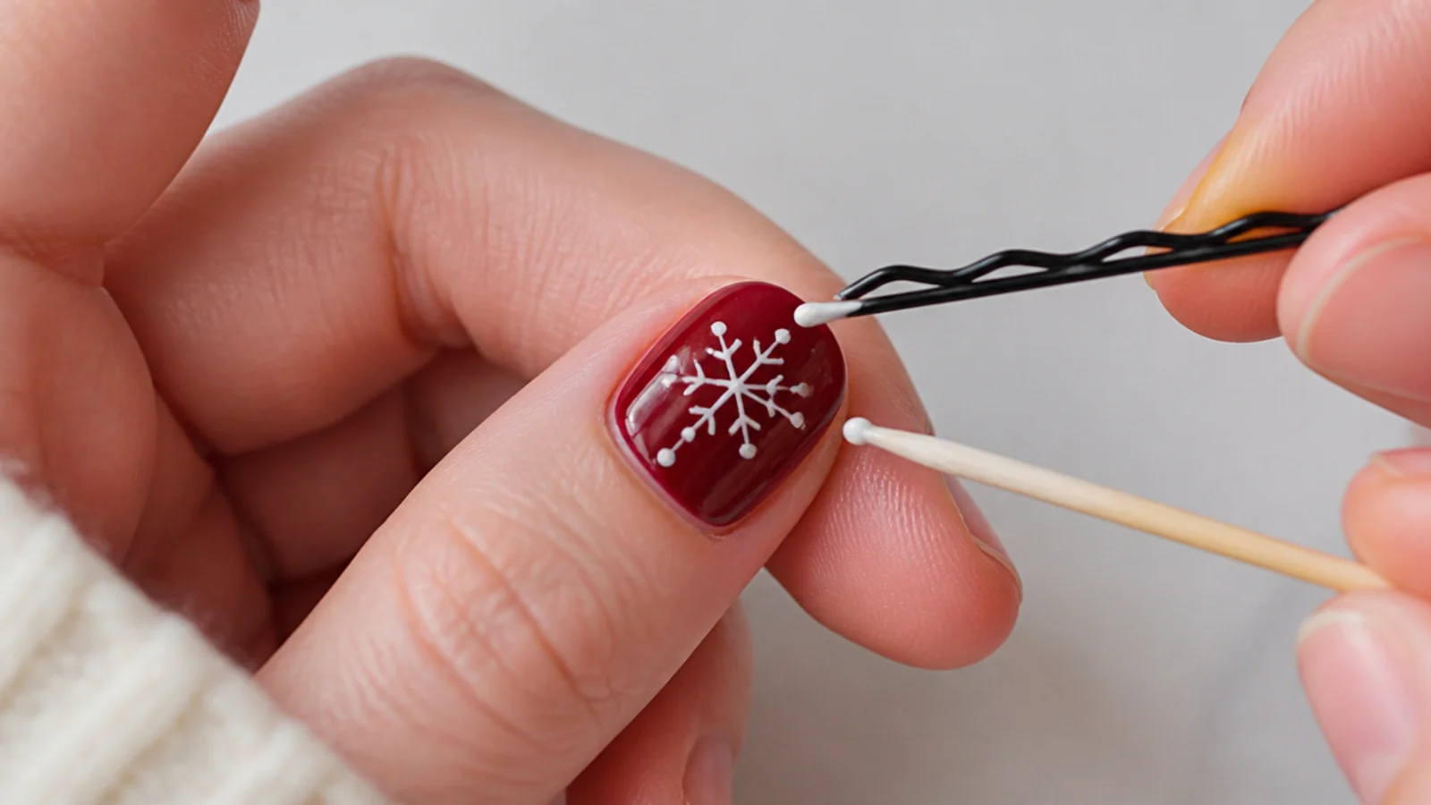 A bobby pin and toothpick making white snowflake dots on a short nail