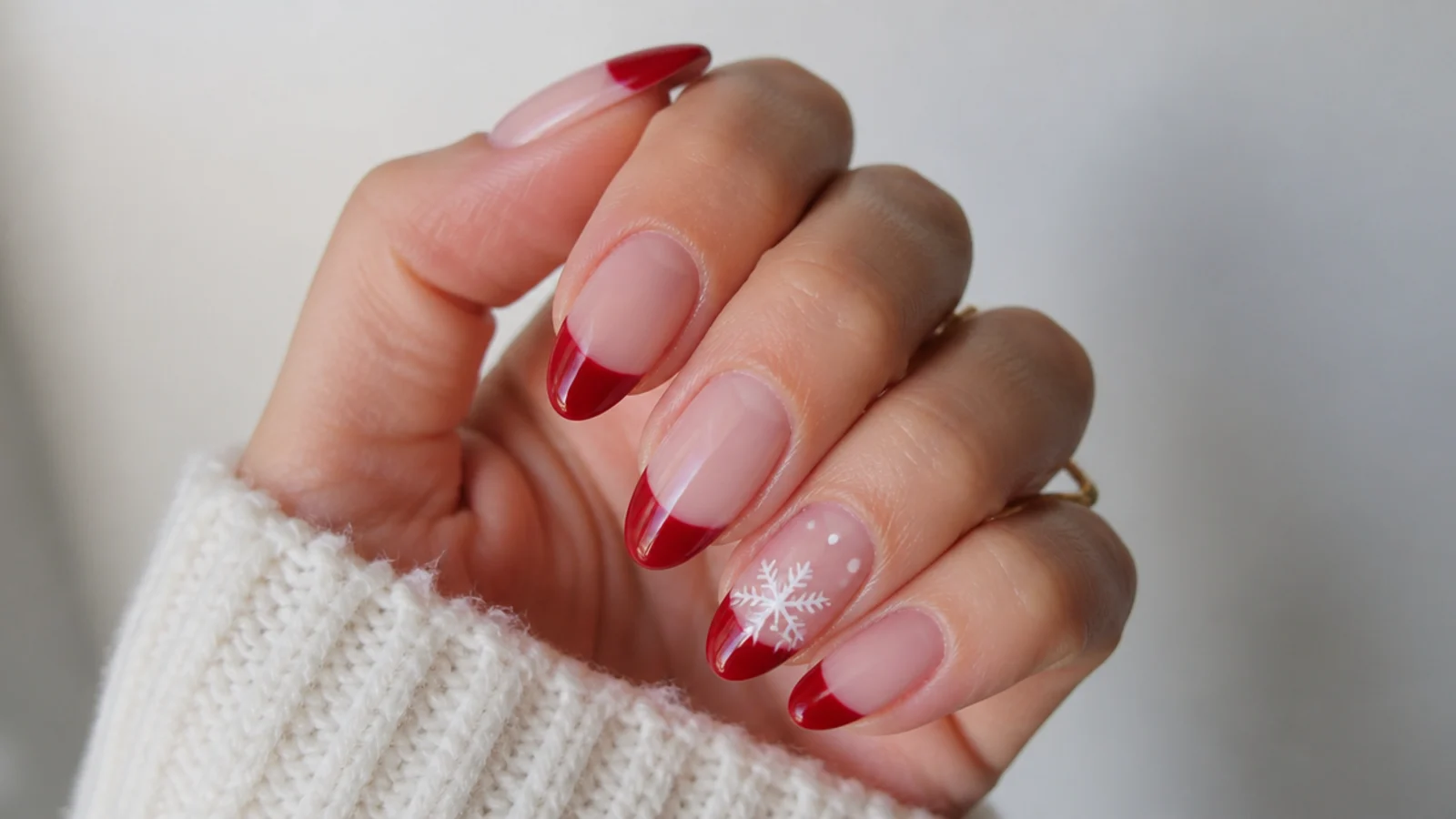 Red French tips with a white snowflake accent, festive nails
