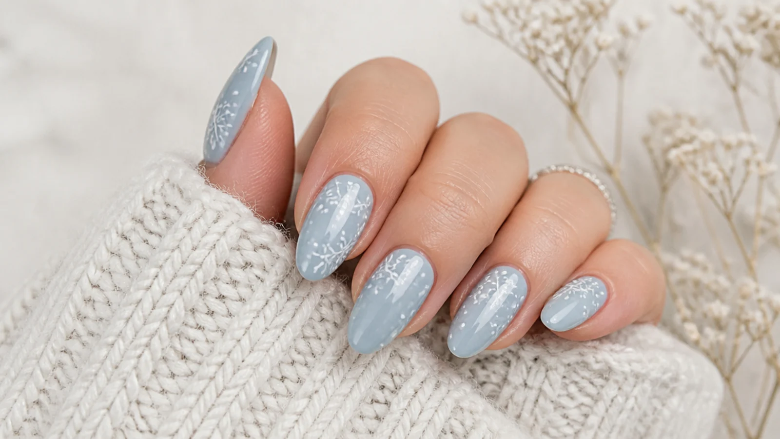 Simple white snowflake nails on an icy blue base, almond shape