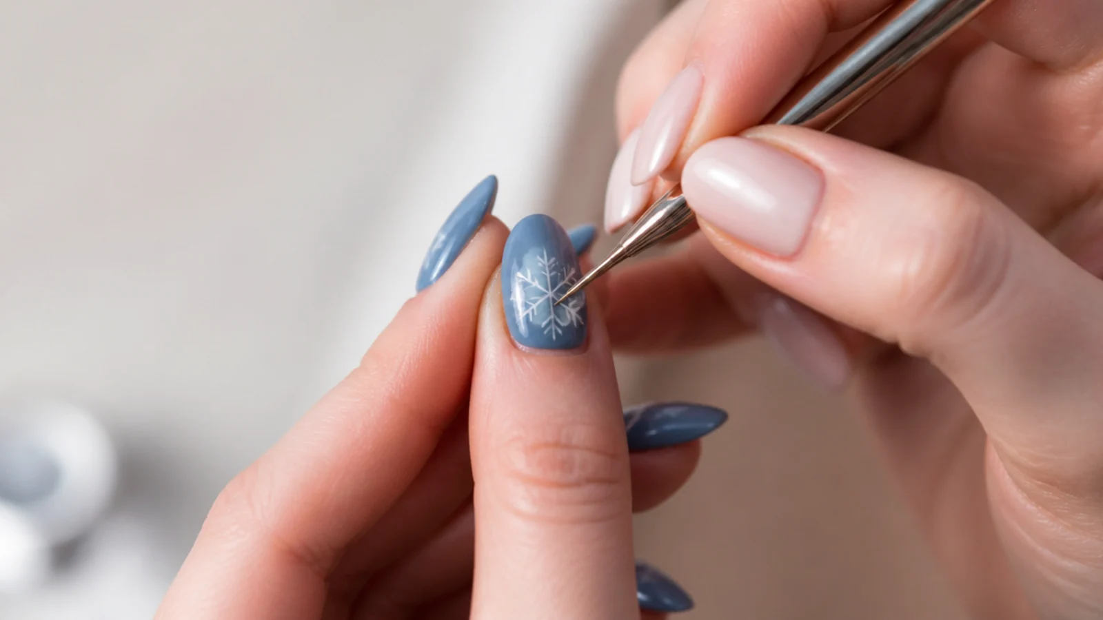 A hand drawing a white snowflake plus sign and diagonals on a blue nail
