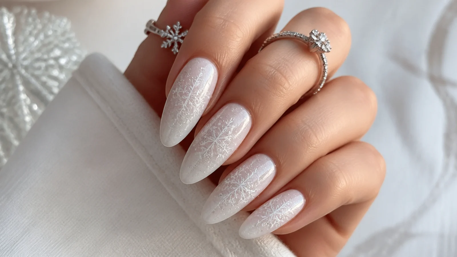 White acrylic nails with tonal white snowflakes and silver shimmer