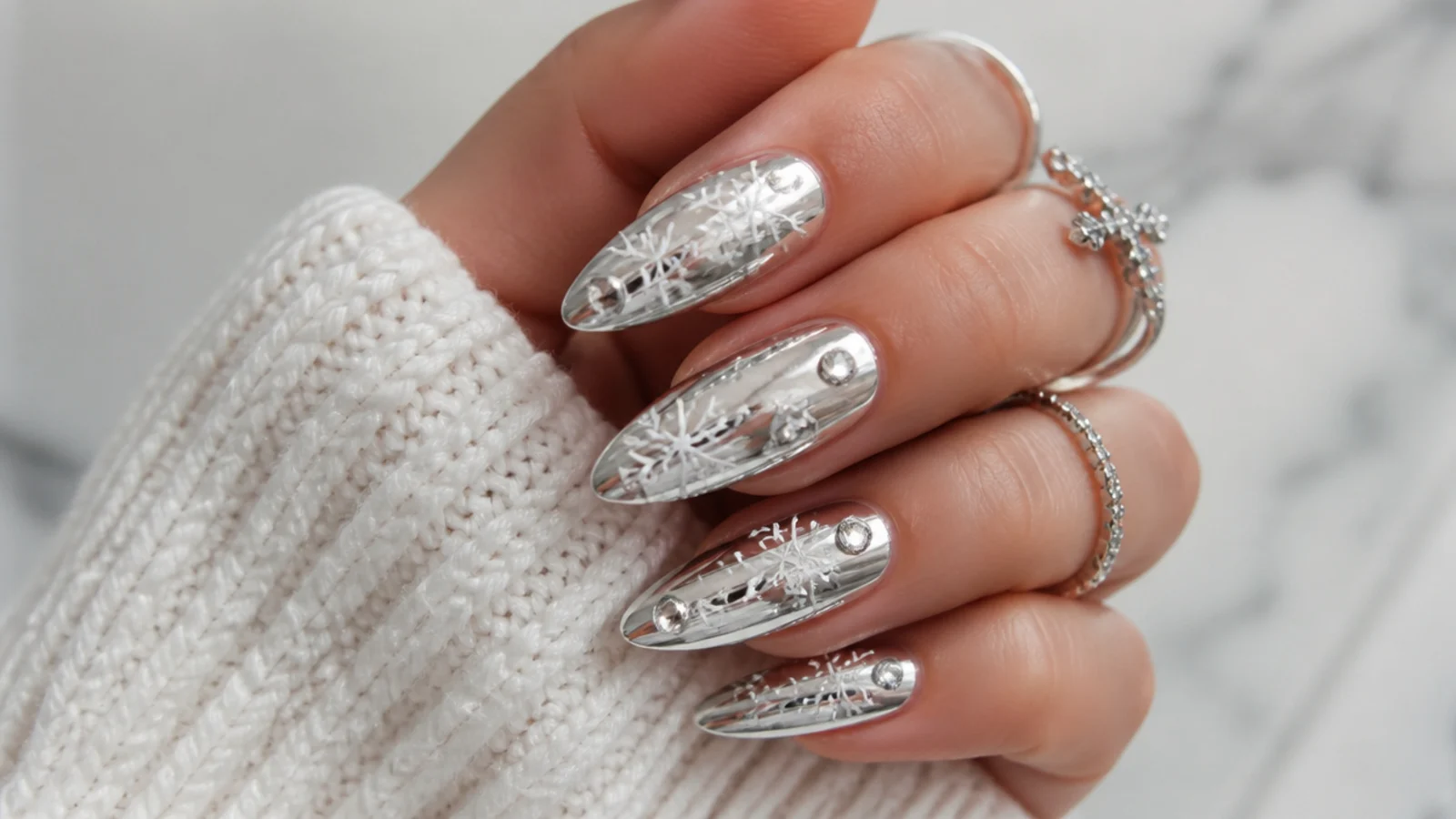 Silver chrome acrylic nails with white snowflakes and rhinestones