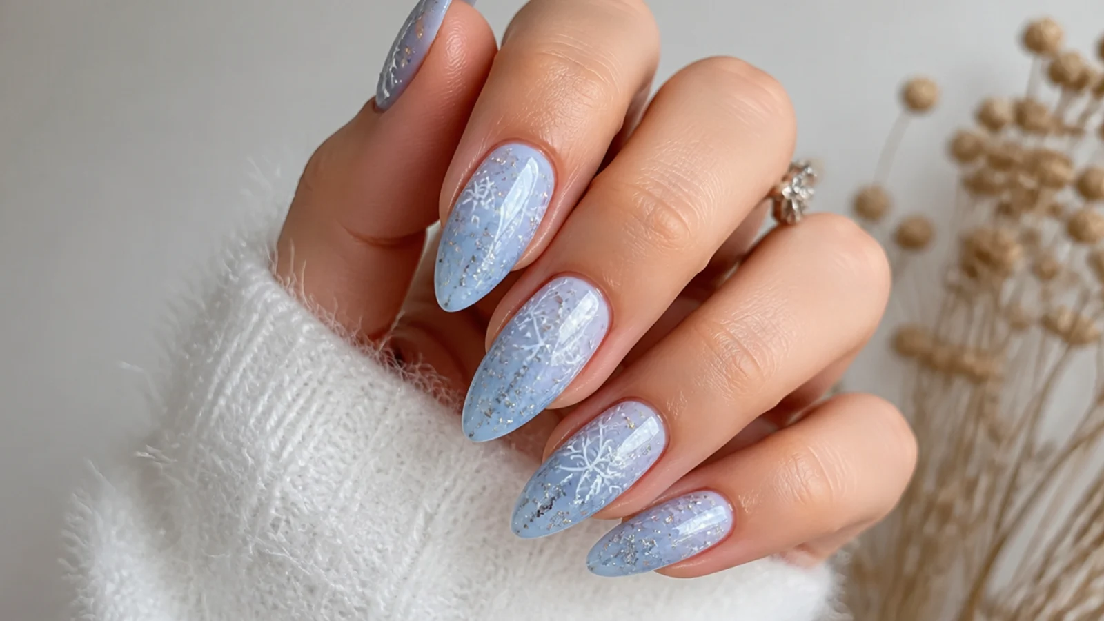 Icy blue snowflake nails with fine white and silver flakes on an almond shape