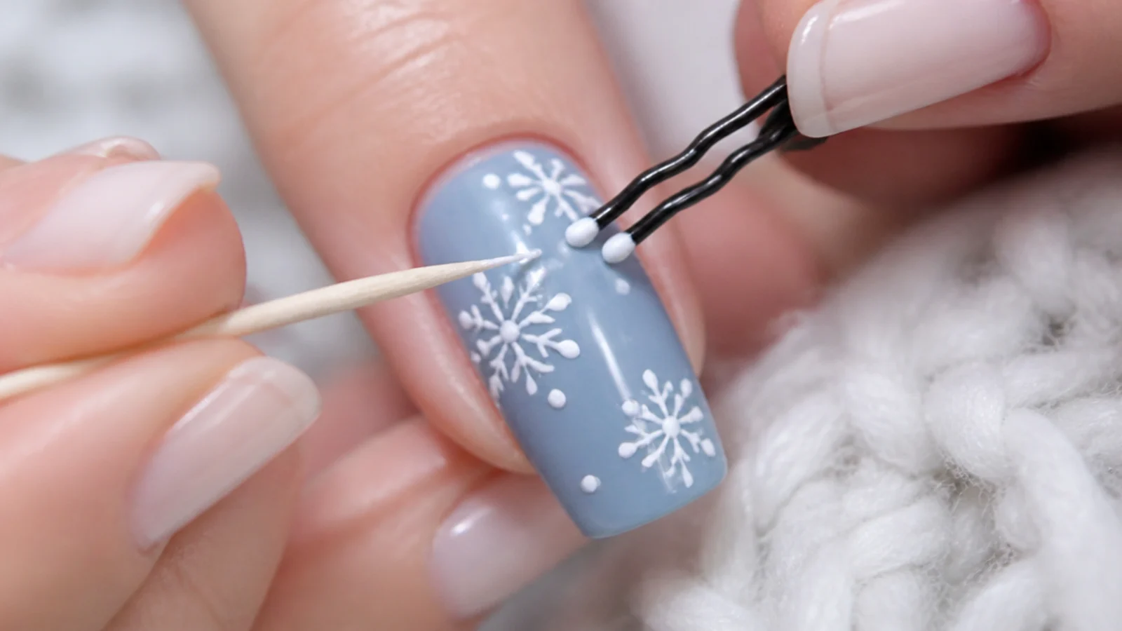 A bobby pin and toothpick making snowflake dots on a painted nail