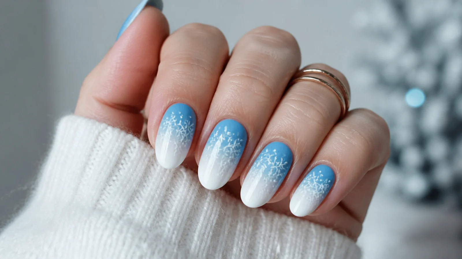 White snowflakes over a blue-to-white ombre base on almond nails