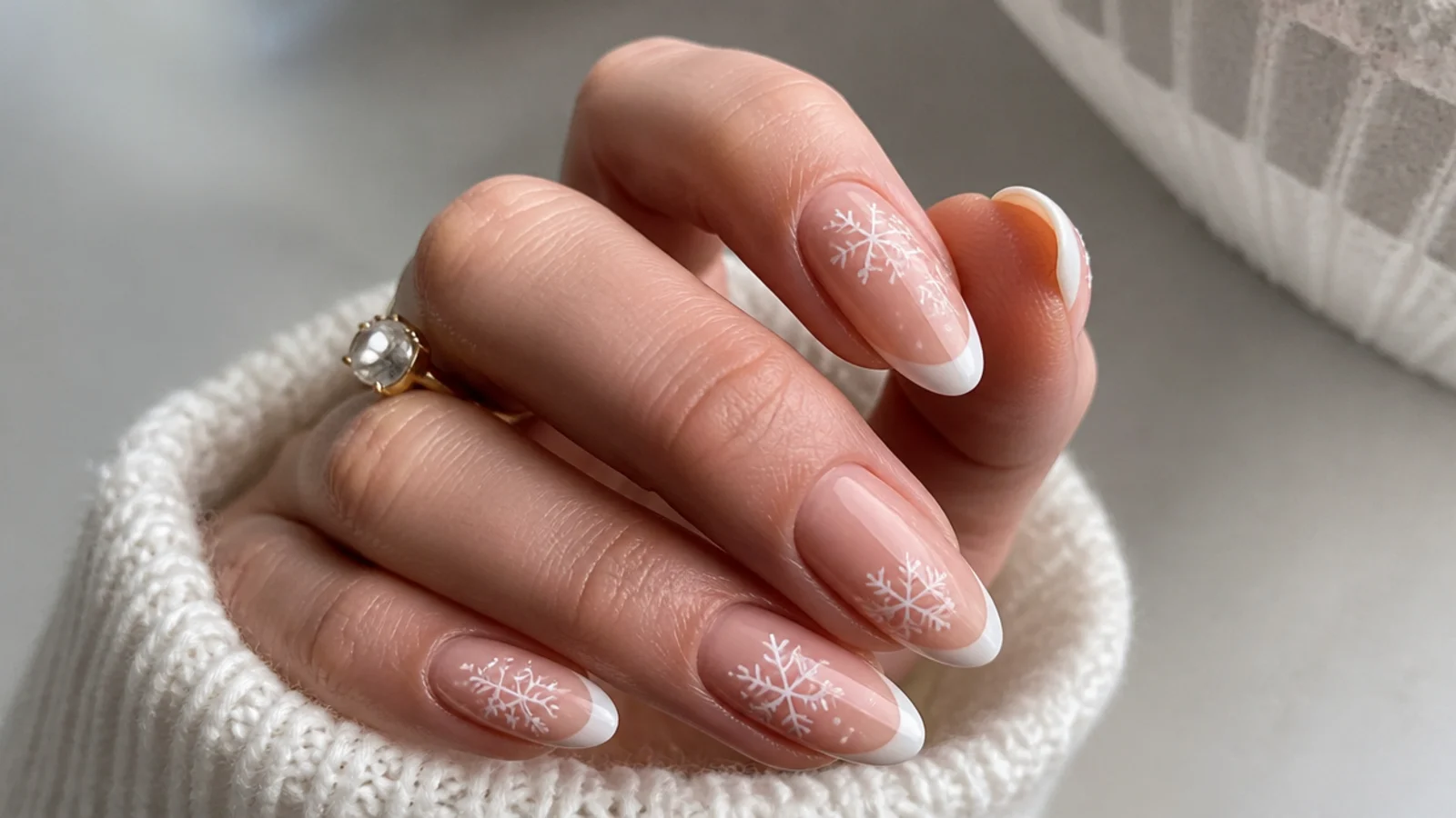 White snowflakes over a nude base with white French tips on almond nails