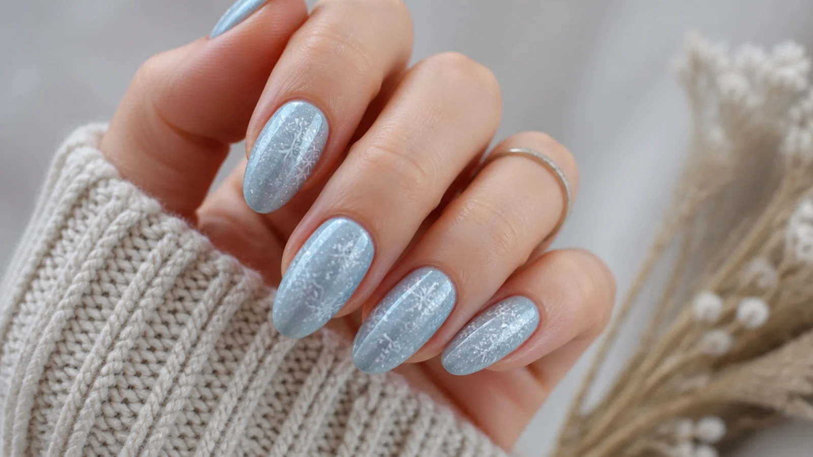 White snowflake nails painted over an icy blue base on almond nails