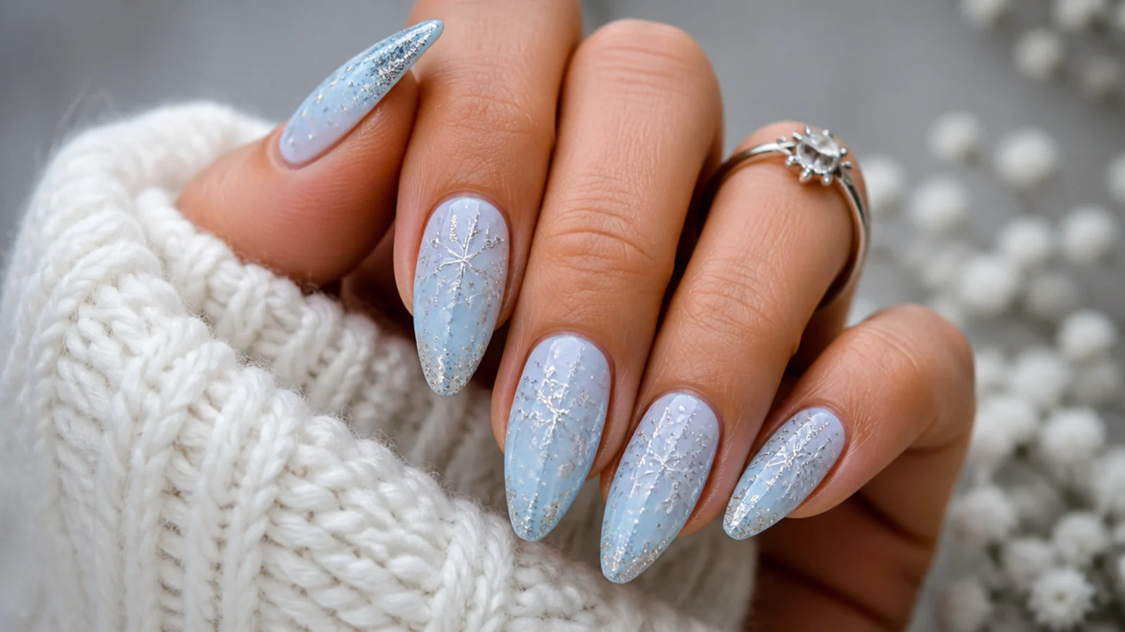 Icy blue winter snowflake nails with fine silver snowflakes on an almond shape