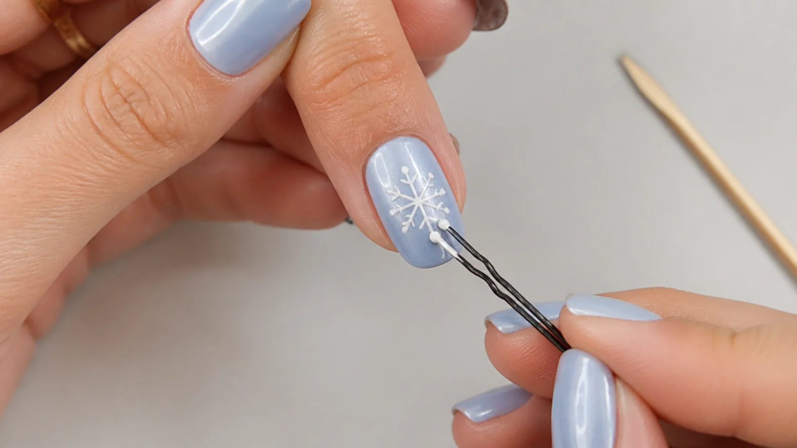 A bobby pin and toothpick drawing snowflake dots on a nail without a dotting tool