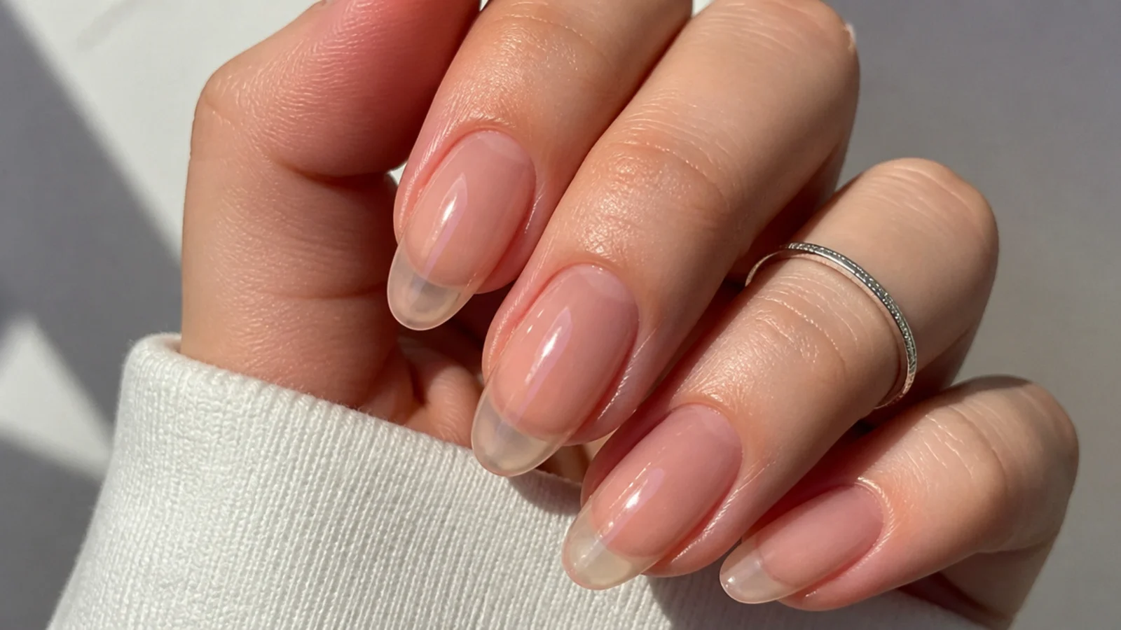 Ultra-sheer glassy almond nail showing the natural nail and free edge through the polish