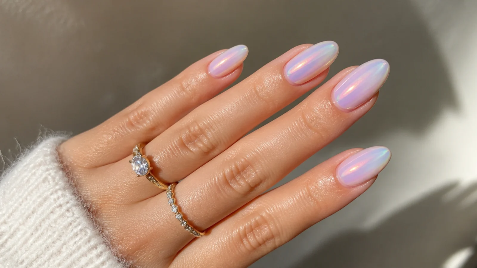 Sheer opal iridescent soap bubble nails flashing pink and blue on an almond shape