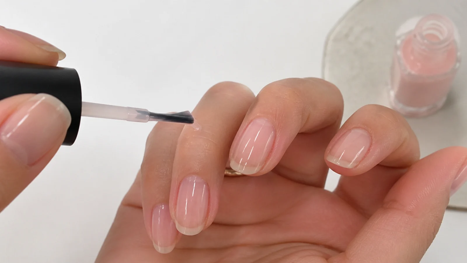 A first ultra-thin sheer coat being floated over the nail leaving the free edge visible