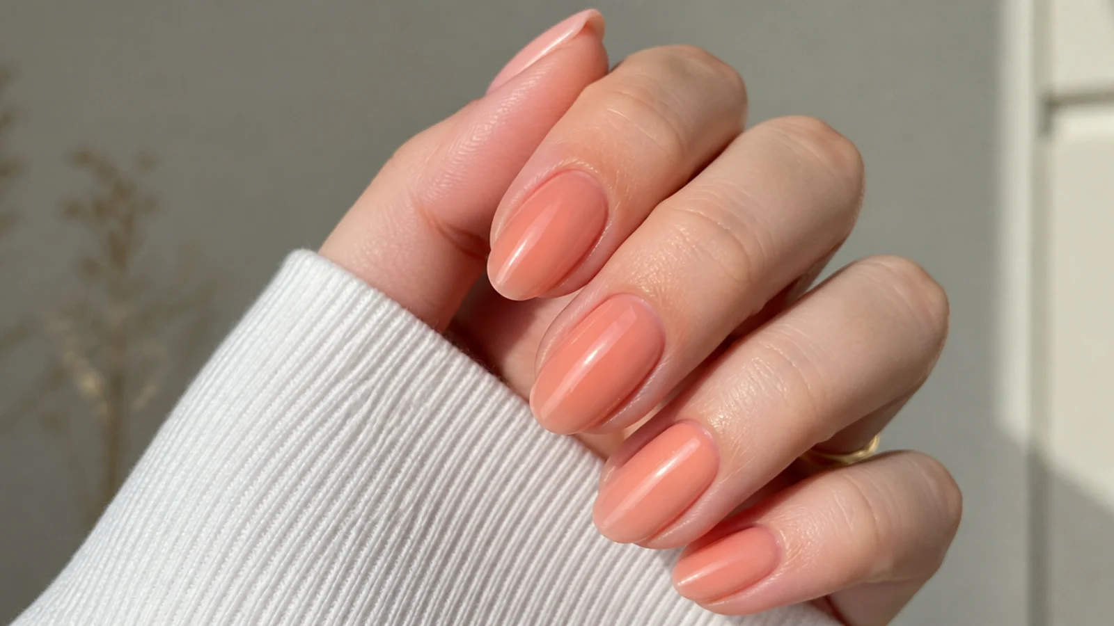Oval nails in a sheer warm peach soap finish glowing on fair skin