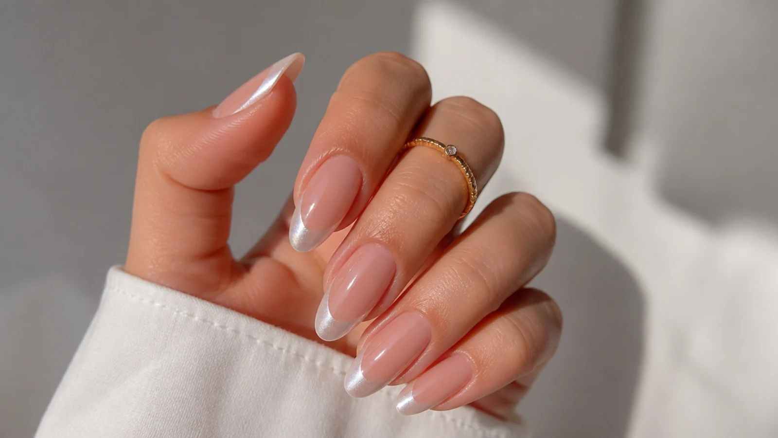 Nude nails with pearl white chrome French tips on an almond shape