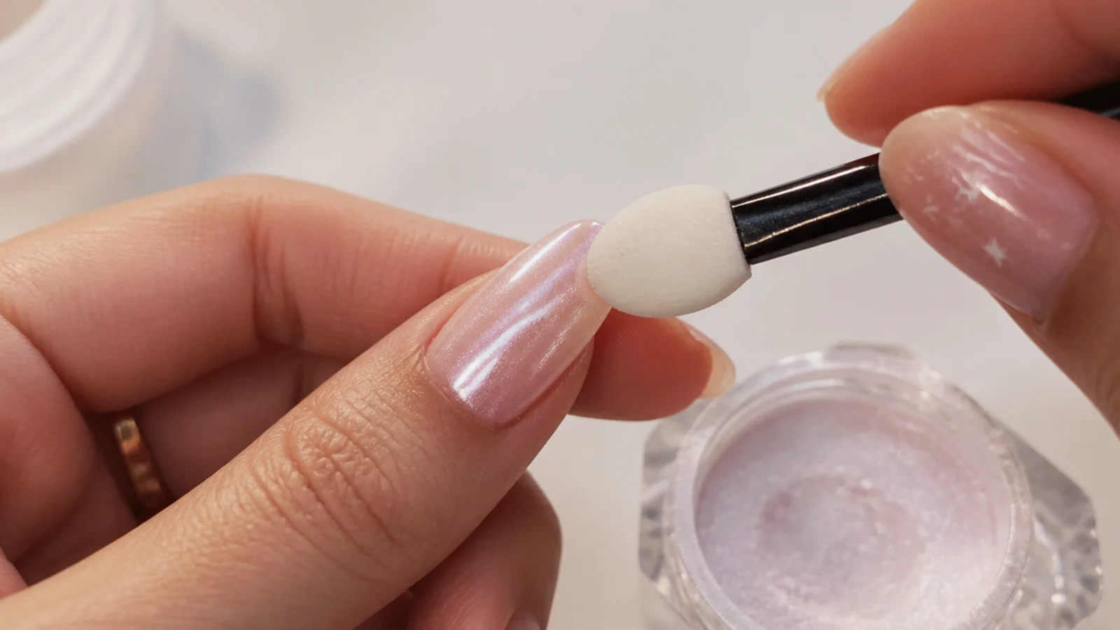 Fine pearl chrome powder being rubbed over a cured nail to a glassy sheen