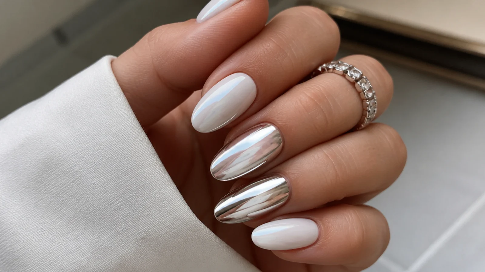 A soft milky white chrome nail beside a bright mirror silver chrome nail