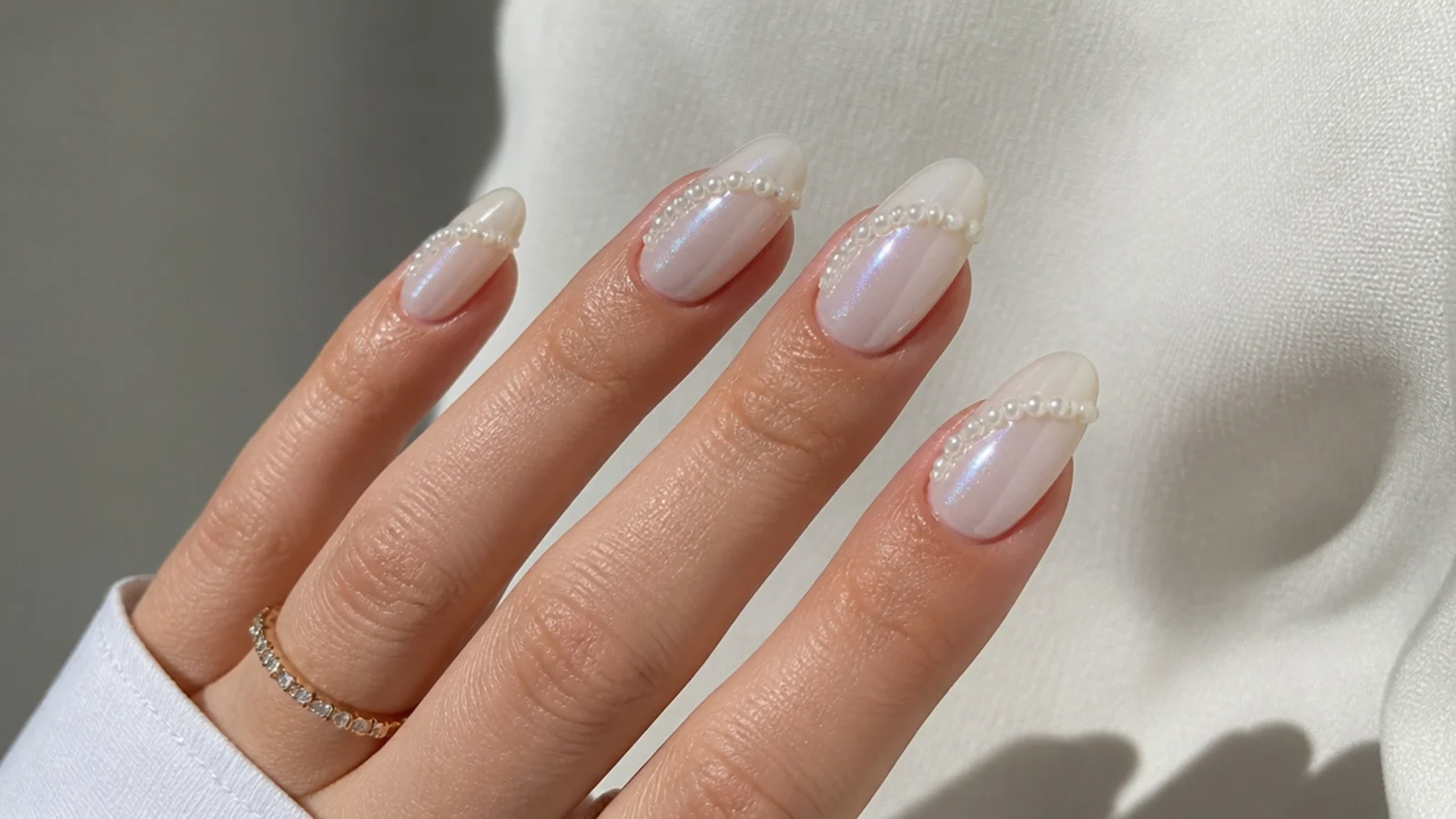 Milky white chrome nails with a curved pearl swirl French design