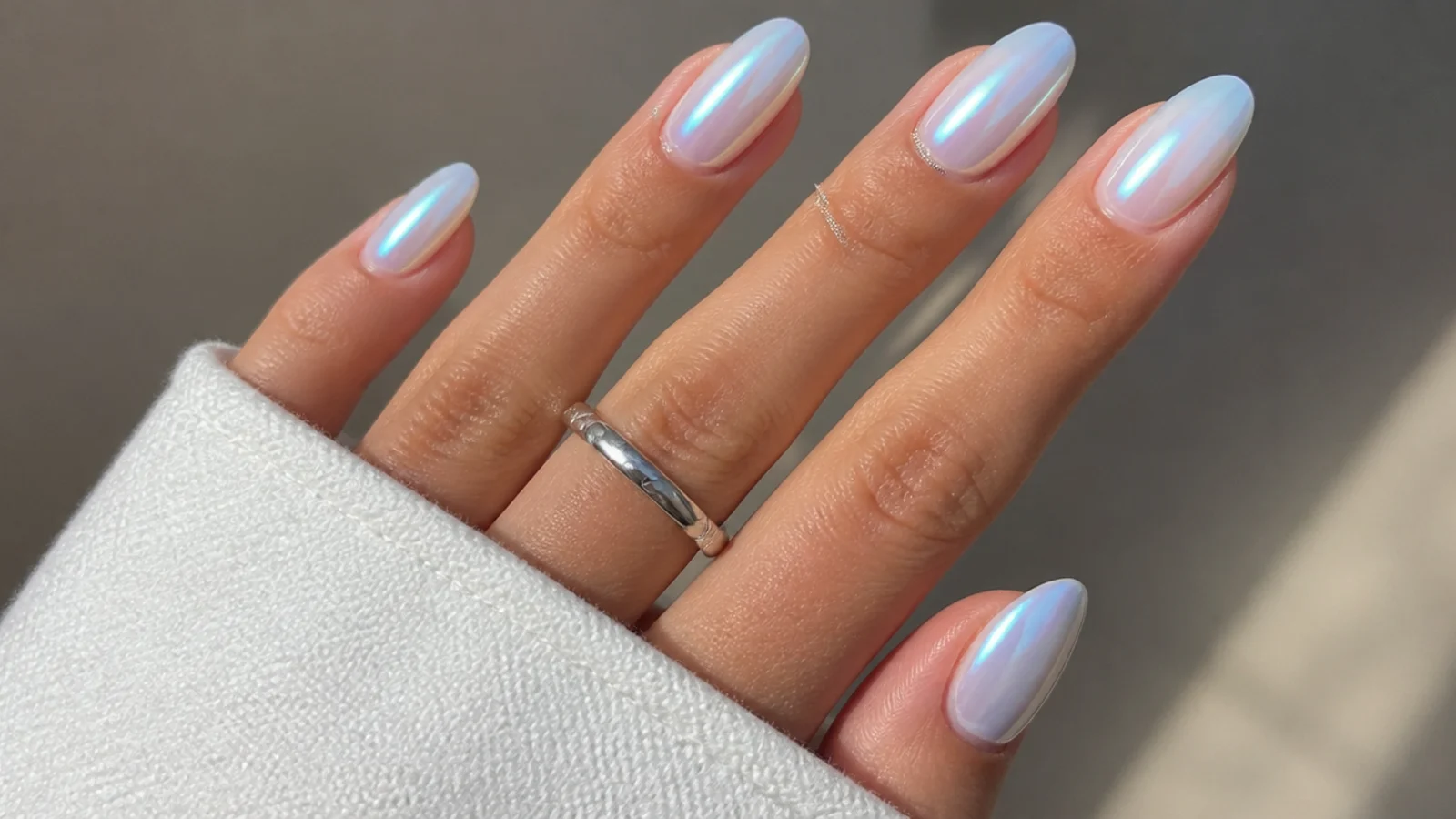 Cool-toned icy milky white chrome nails with a blue-silver pearl glow