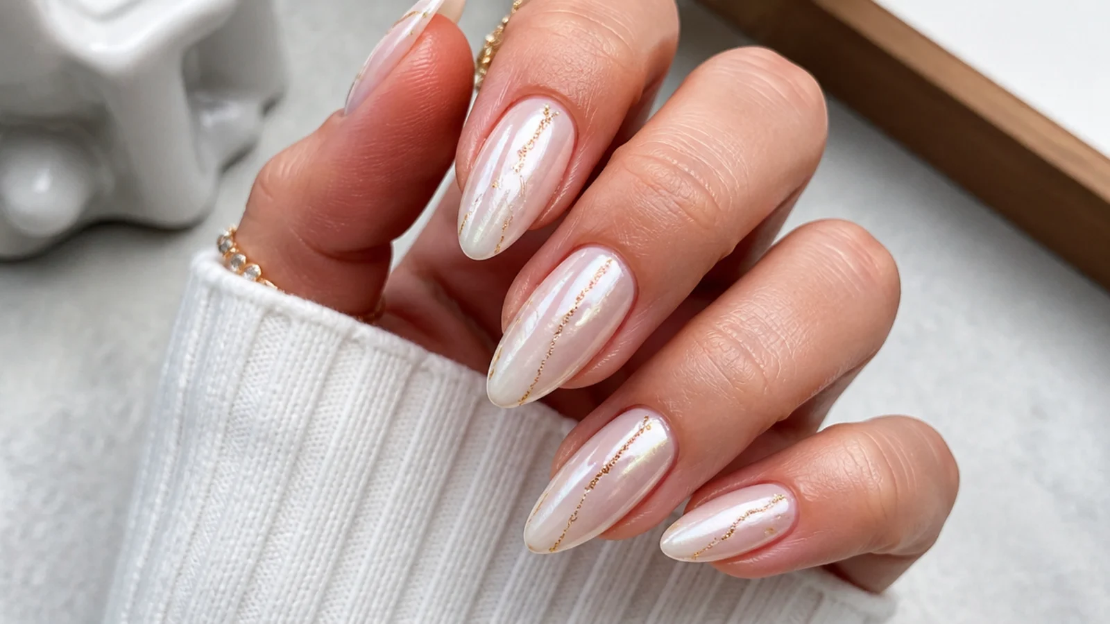Milky white chrome nails with thin gold foil accent lines