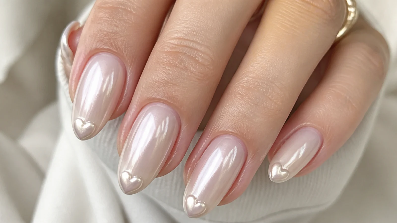 Milky white chrome nails with a small pearl chrome heart at the tip