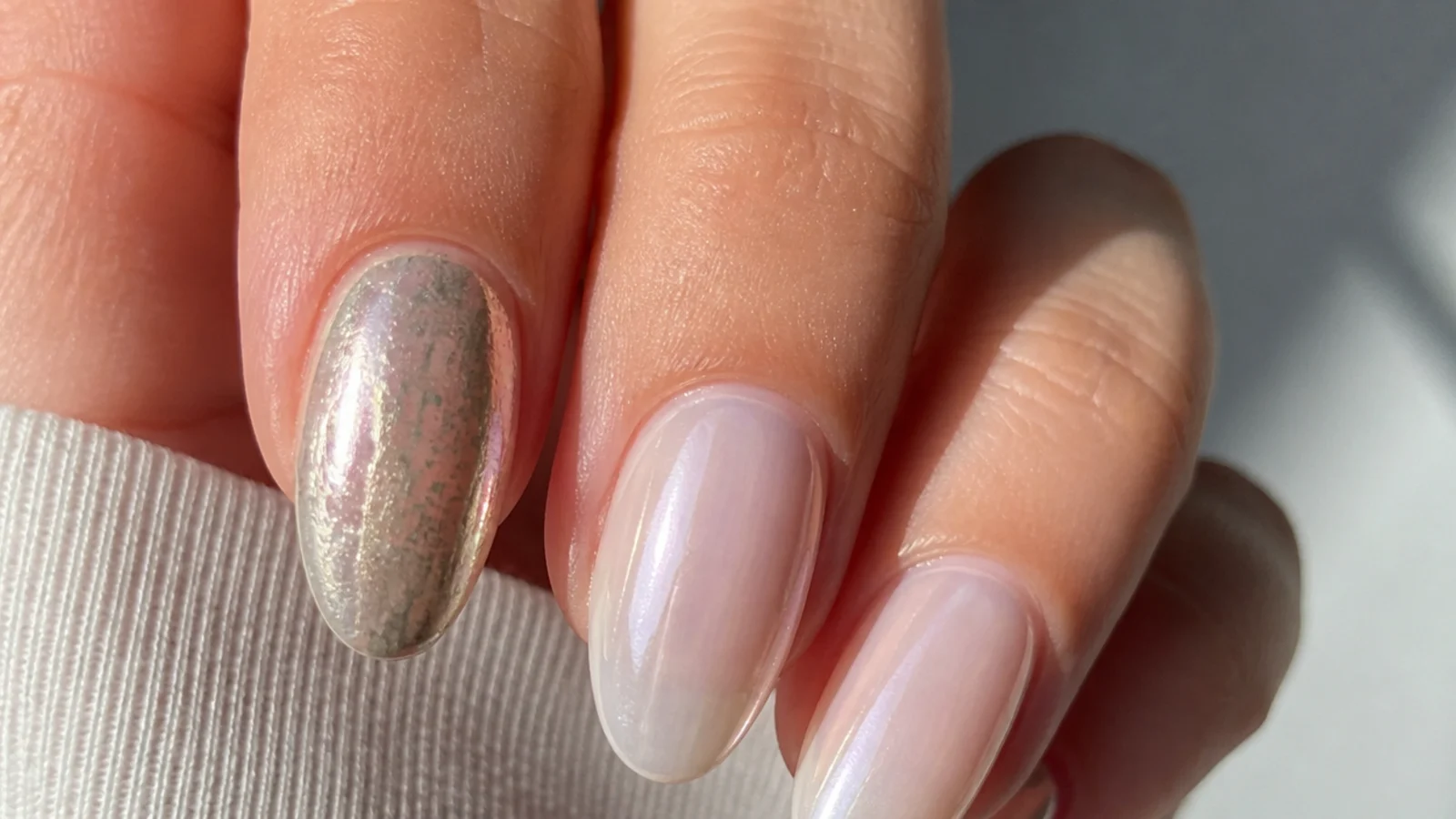 A dull patchy chrome nail next to a smooth glassy milky chrome nail