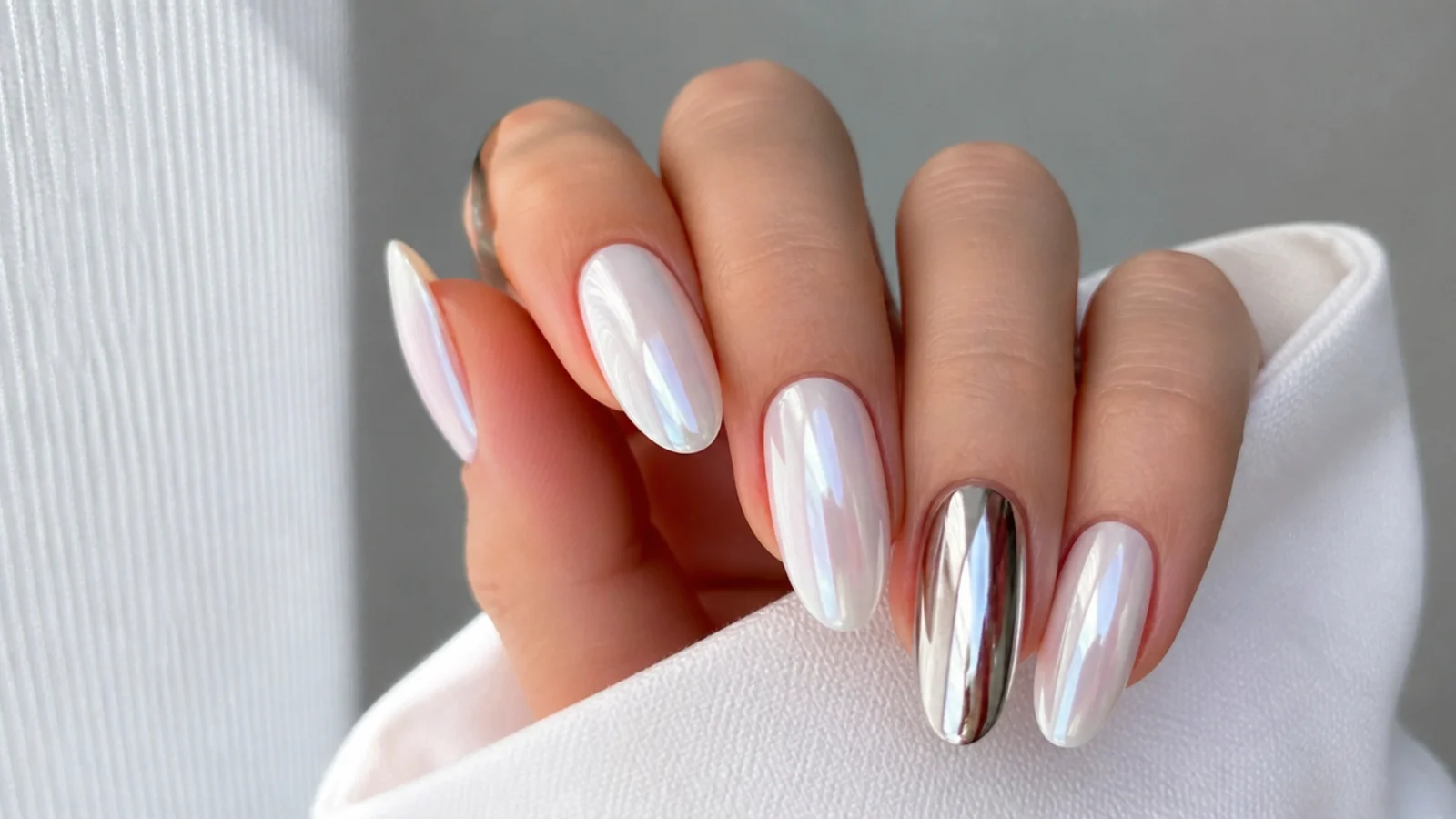 Soft milky white chrome nail beside a bright silver mirror chrome nail