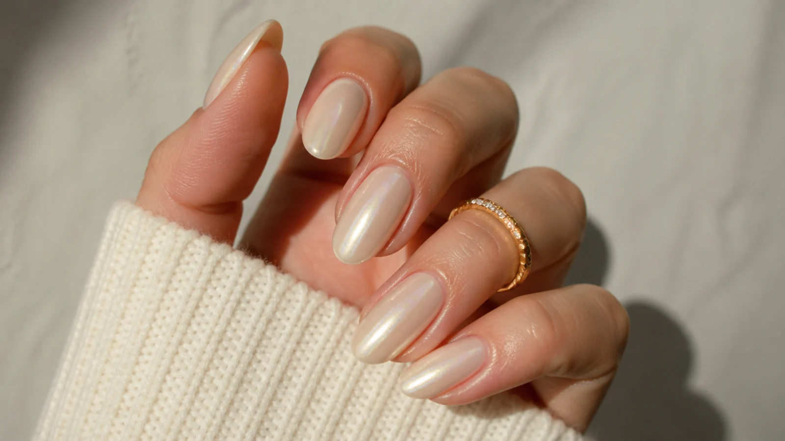 Warm off white chrome nails with a champagne pearl glow on almond nails