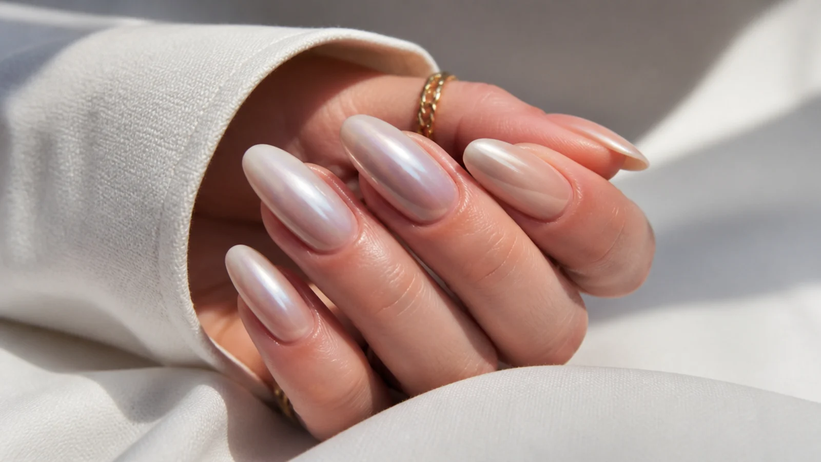 Off white chrome nails with a soft dusty mauve pearl undertone on almond nails