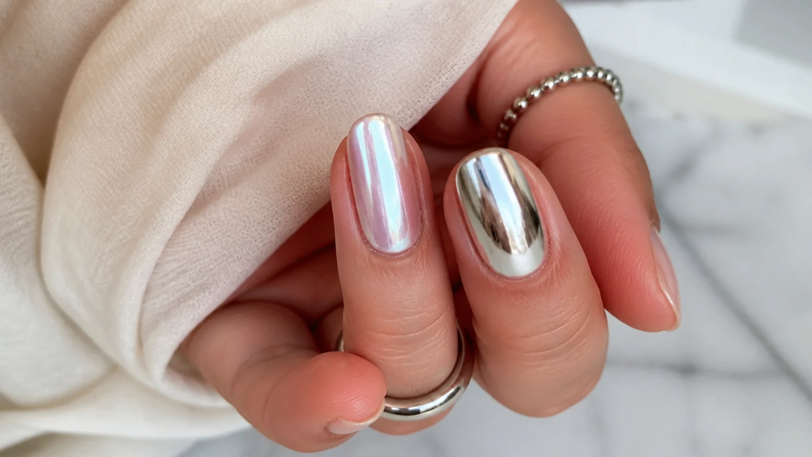 Soft milky pearl chrome nail beside a hard silver mirror chrome nail