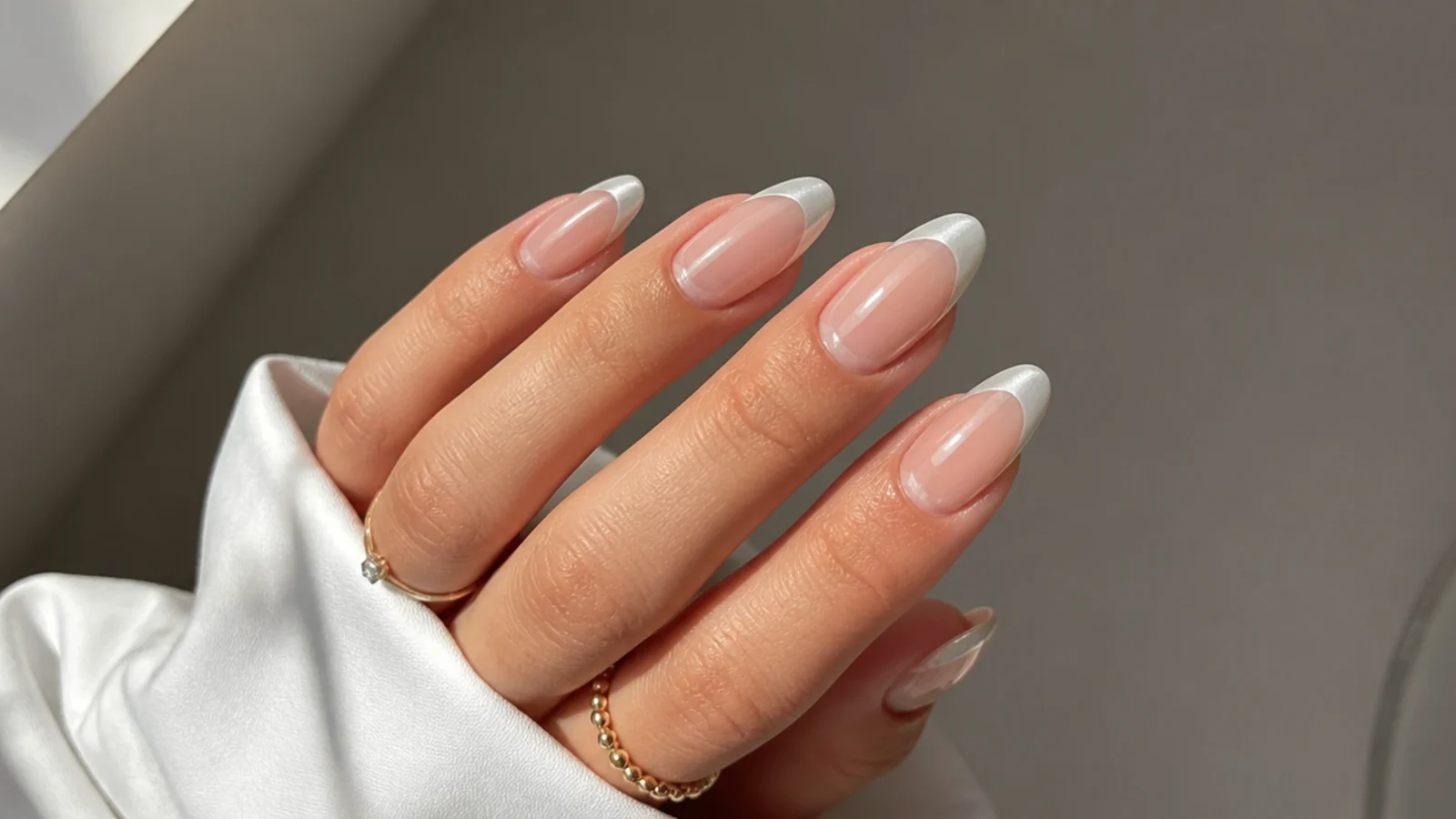 Almond French nails with pearl white chrome tips over a sheer base