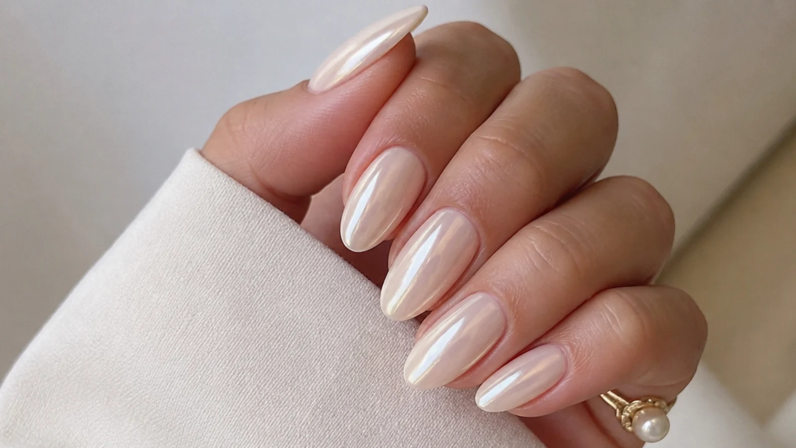 Warm off-white cream almond nails with a pearl chrome sheen
