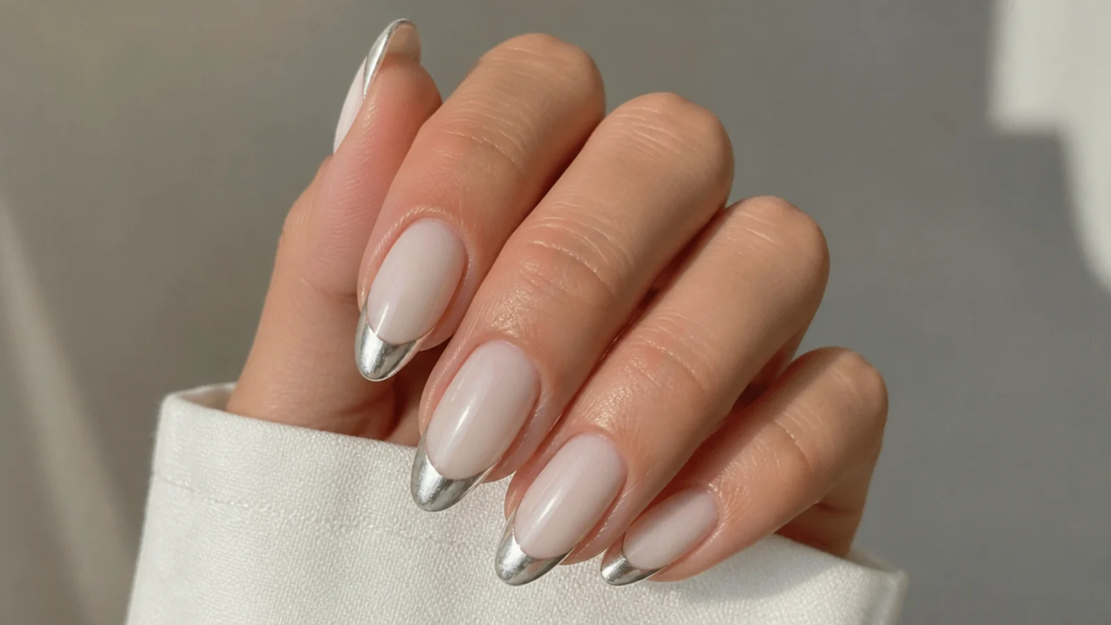 Almond nails with a milky white body and pearl chrome French tip
