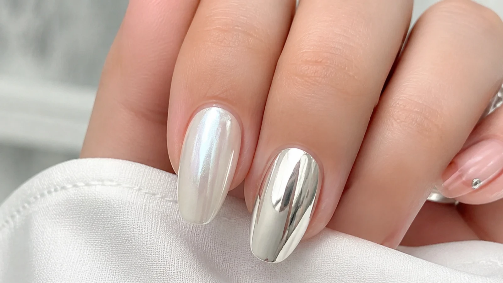 Soft pearl white chrome nail beside a bright mirror silver chrome nail