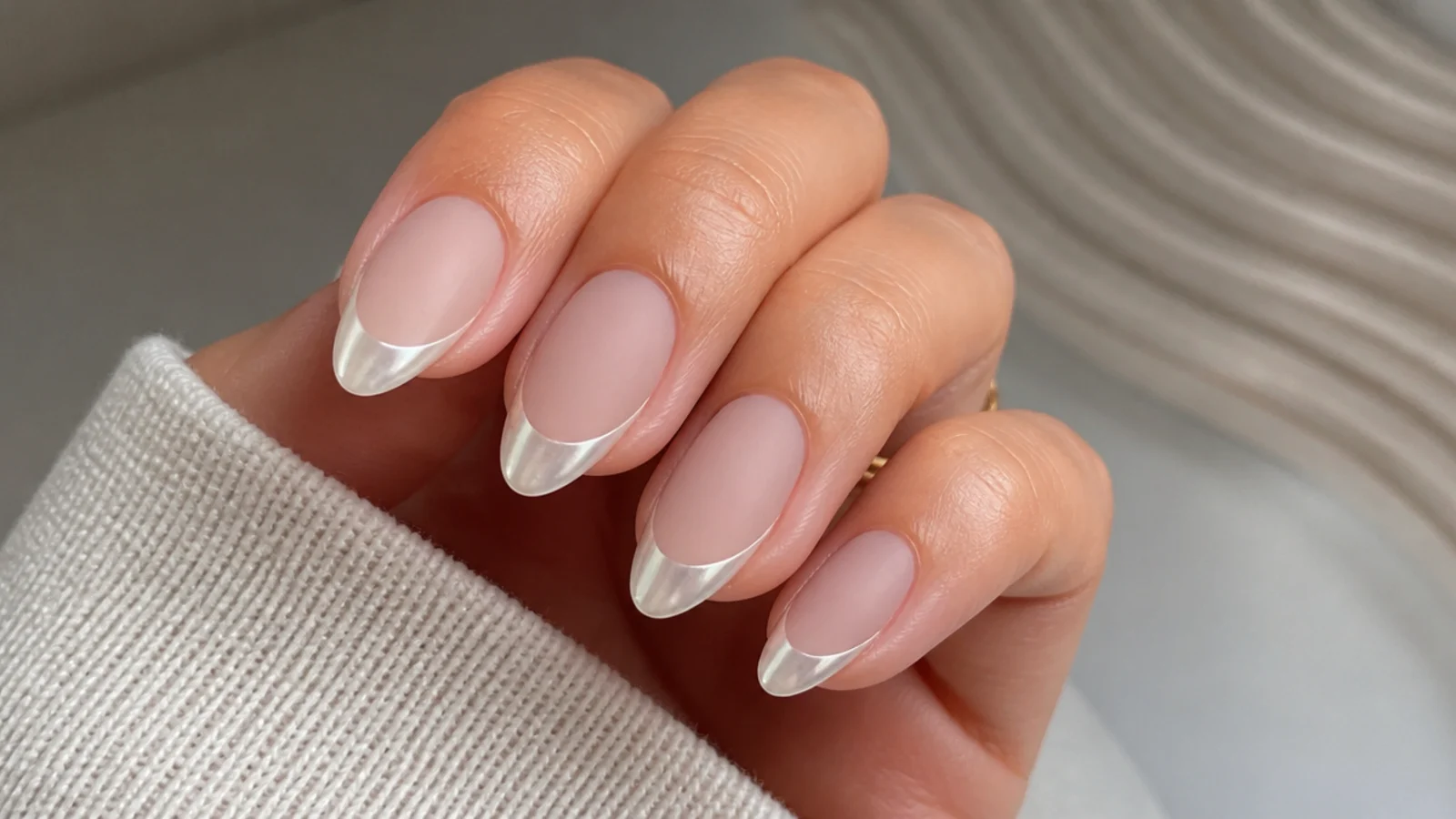 Almond nails with a matte nude base and a glossy pearl chrome french tip